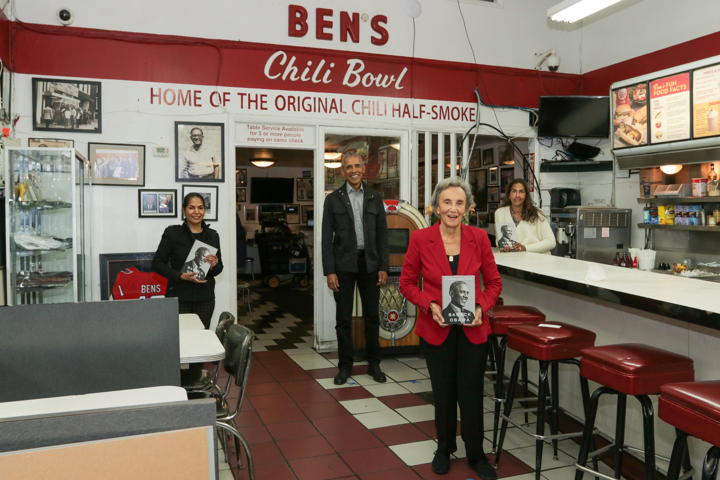 President Obama stands behind three woman in their restaurant